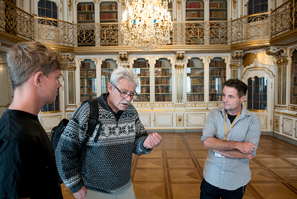 Barnebarnet Tinus Behrendt, tv, og sønnen Martin Behrendt th, lytter interesseret til Flemming Jensens anekdoter med mange opgaver på Christiansborg.