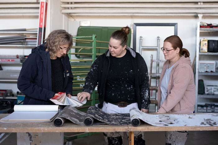 Malersvend Ellen Hempler Eldrup Wexø – i midten - har været i Elisabeth’s Malerfirma i seks år. Hun er glad for kollegerne og trives med en mester, der tydeligt fortæller, hvordan arbejdet forventes udført. Foto Alex Tran